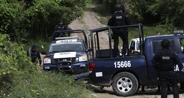 Federal police stand guard next to vehicles on a road at an area near clandestine graves at Pueblo Viejo, in the outskirts of Iguala, southern Mexican state of Guerrero